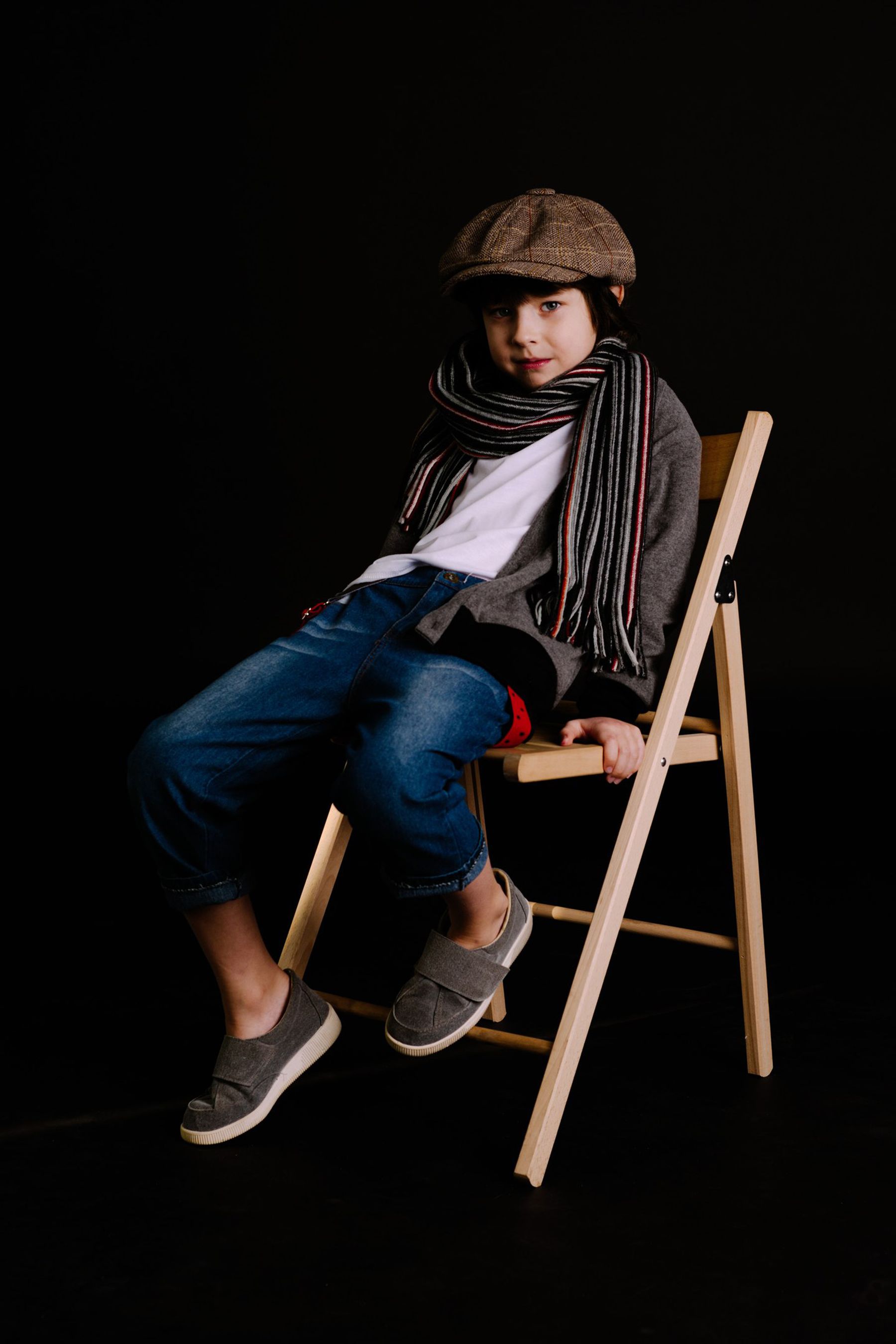 Young model in a newsboy cap posing on a chair