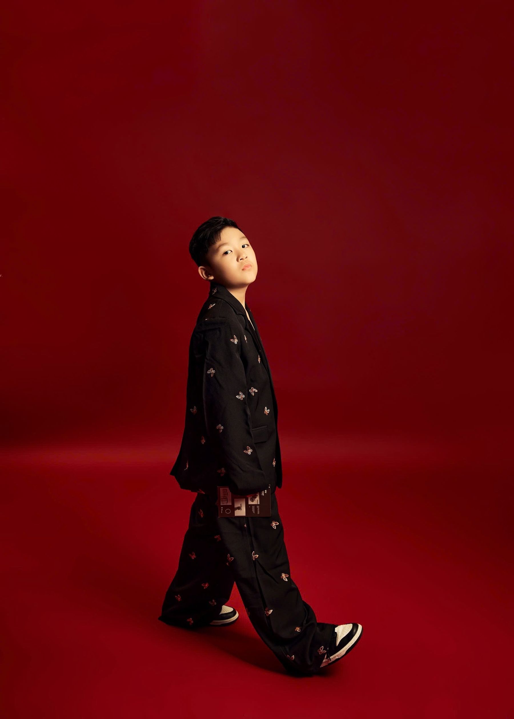 Kid model walking against a red editorial backdrop