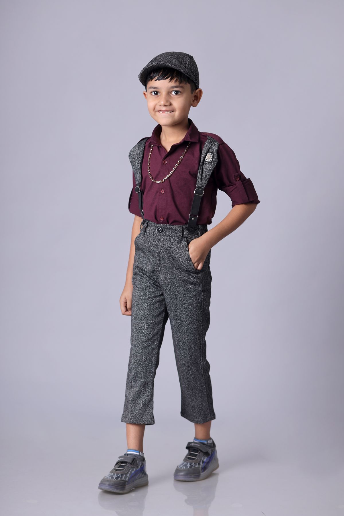 Stylish young boy posing in a classic outfit with cap and suspenders