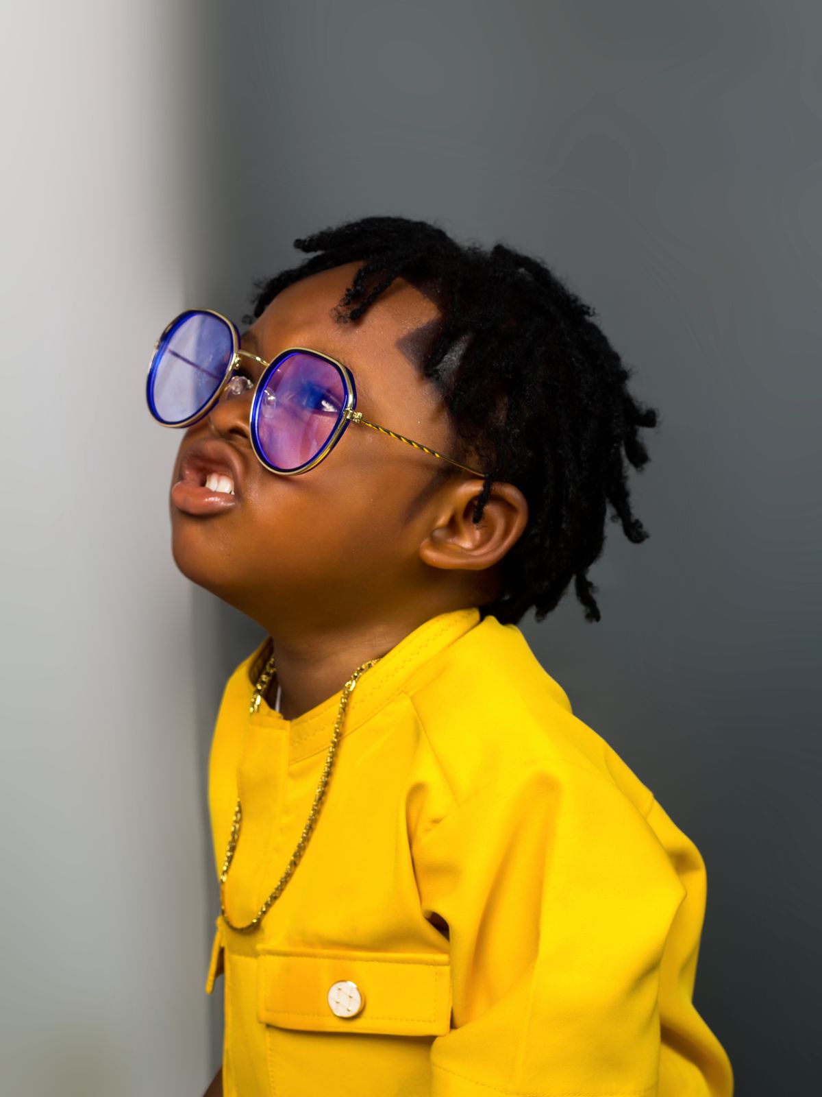 Confident kid in a bright yellow outfit and blue sunglasses